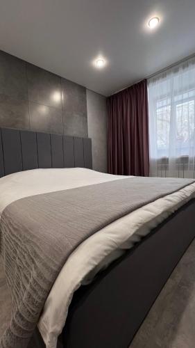 a bedroom with a large bed and a window at Новая квартира в минуте от Мечети, Достыка, Самовара, Coffee Boom , Хуторка, Прокуратуры, Налоговой, Акимат города, ЦУМа in Petropavlovsk