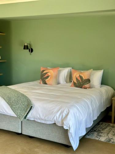 a bed with white sheets and colorful pillows at Stylish Cottage on secure estate in Howick