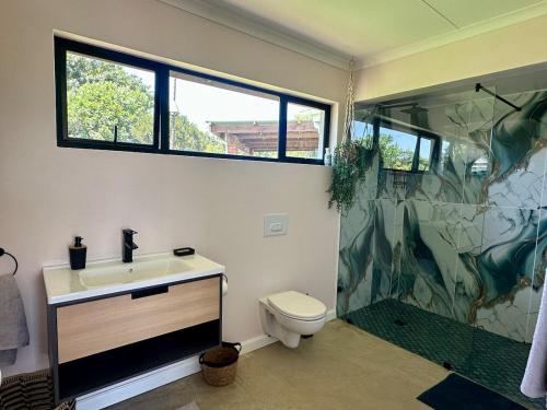 a bathroom with a sink and a shower and a toilet at Stylish Cottage on secure estate in Howick