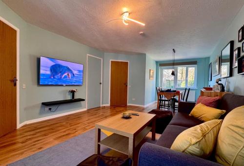 a living room with a couch and a tv on the wall at Lovely 2 bedroom house in Bath with private parking garden WiFi & easy access to city centre in Bath