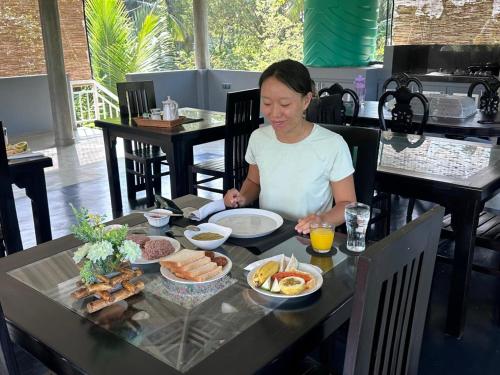een vrouw die aan een tafel zit met een bord eten bij Villa cork in Galle