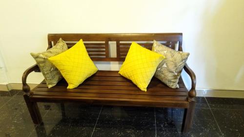 a wooden bench with four yellow pillows on it at Taprobana Transit in Katunayake