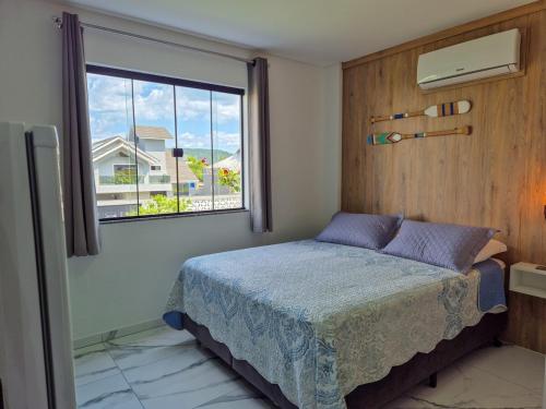a bedroom with a bed and a window at Águas de Canto Grande in Bombinhas