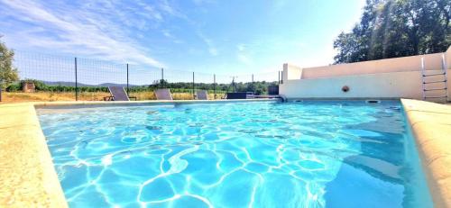 une piscine avec de l'eau bleue devant un immeuble dans l'établissement Escapades en Ventoux, à Venasque