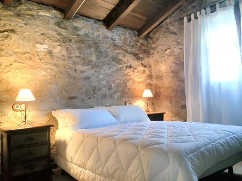 a bedroom with a white bed and a stone wall at Comfortable House with Shared Pool in Alcaracejos in Alcaracejos