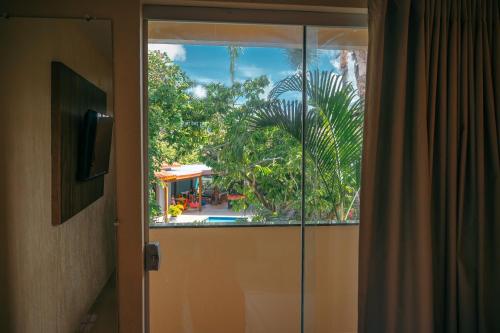 a sliding glass door with a view of a house at Ayla Praia Hotel Centro Porto Segur in Porto Seguro