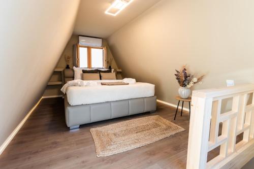 a attic bedroom with a bed and a window at Paplanka Boutique Cabin in Nyírbátor
