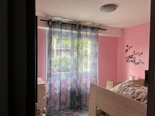 - une chambre avec un lit et une fenêtre avec un rideau dans l'établissement T4 a Ferney Voltaire a 10 mn de Geneve, à Ferney-Voltaire