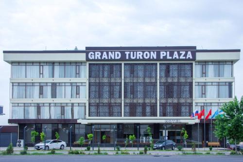 a grand trump plaza building with cars parked in front at Grand Turon Plaza Hotel in Tashkent