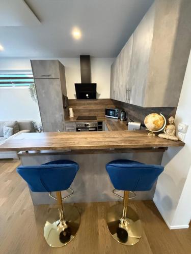 a kitchen with a counter and two blue bar stools at Ferienhaus am Seepark -J&K in Goch