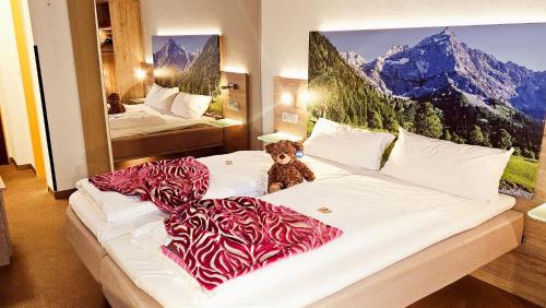 a teddy bear sitting on a bed in a hotel room at Hotel Edel Weiss in Bremen