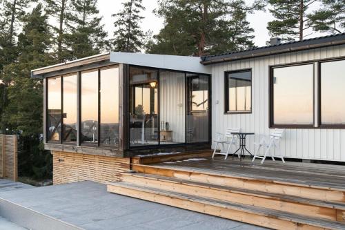 a house with glass windows and a table on a deck at Oceanfront Escape with Sauna & Jacuzzi in Stavsnäs