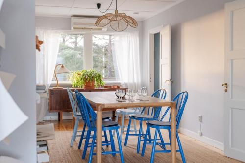 a dining room with a wooden table and blue chairs at Oceanfront Escape with Sauna & Jacuzzi in Stavsnäs