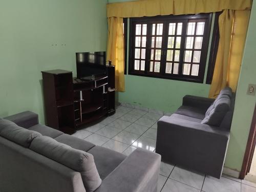 Una sala de estar con dos sofás y un televisor. en BONA CASA PERUÍBE, en Peruíbe