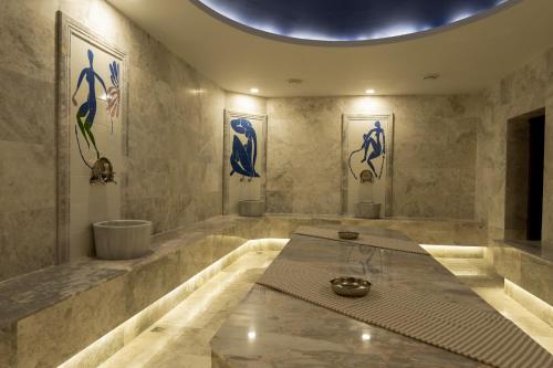 a bathroom with a large tub and paintings on the walls at Asmalı Konak Cave Suites in Urgup