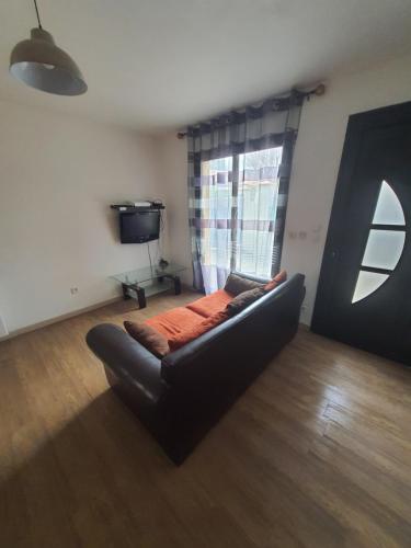 un canapé noir dans un salon avec une fenêtre dans l'établissement Gite le voisin Toulousain 1, à Toulouse