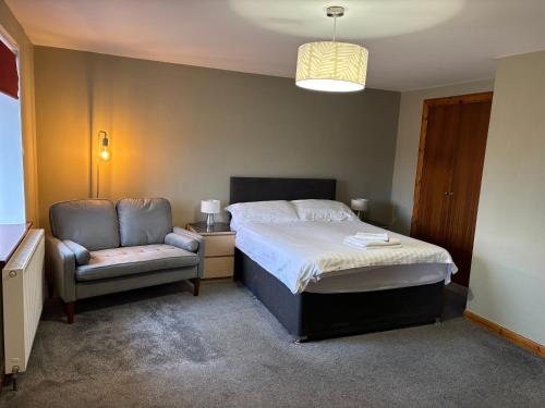 a bedroom with a bed and a chair in it at The Barn Lodge in Stirling