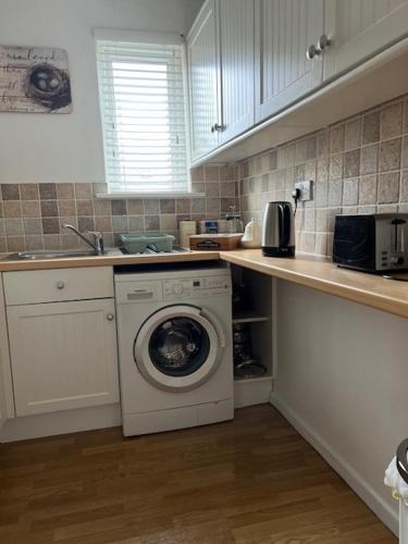 a kitchen with a washing machine and a sink at Beautiful Character Property in Angmering