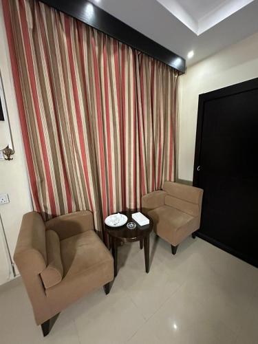 a living room with two chairs and a table and a screen at منازل الحمراء السكنية للشقق المخدومة "إقتصادي" in Buraydah