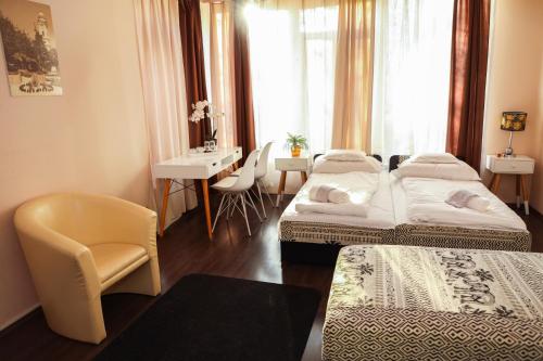 a hotel room with two beds and a table and chairs at Éjjelibagoly Vendégház in Szentes