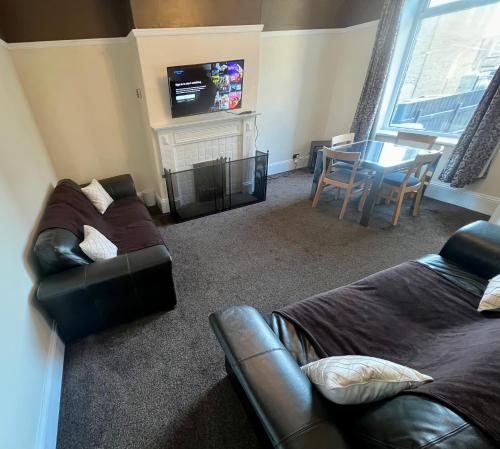 a living room with a couch and a table and a television at Central Halifax Work & Retreat Base - Two bedroom house - sleeps up to 4 - free parking and internet in Halifax
