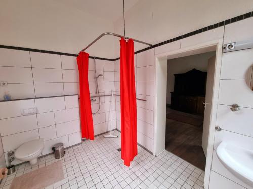 a bathroom with a red shower curtain and a toilet at Das alte Pastorat in Kevelaer