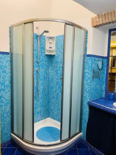 a bathroom with a shower with blue tiles at L'Archetto Apartment in Rieti