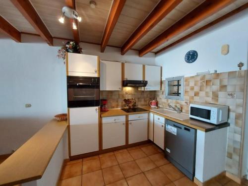 une cuisine avec des armoires blanches et un micro-ondes dans l'établissement Villa confortable 3 pièces, 6 pers, terrasse et parking privé - FR-1-326-411, à Marseillan