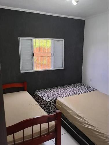 two beds in a room with a window at Chácara bela vista in Socorro