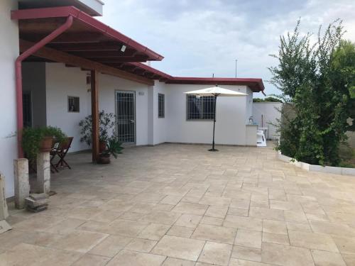 un patio de una casa con sombrilla en Soffio del Mare - Casa Vacanze - Torre Chianca, en Monte Grappa