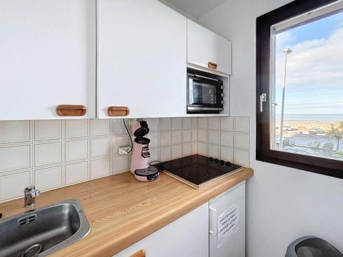 une petite cuisine avec un évier et un micro-ondes dans l'établissement Appartement familial centre ville avec parking et animaux permis - FR-1-465-90, à Merville-Franceville-Plage