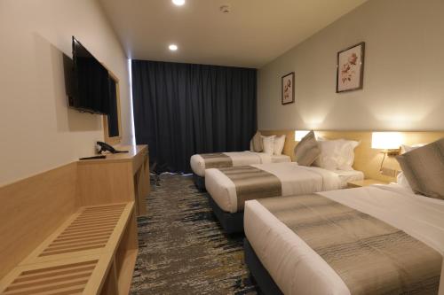 una camera d'albergo con due letti e una TV a schermo piatto di فندق مثابة مكة a La Mecca