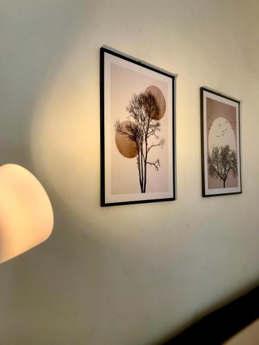 two framed pictures on a wall with a lamp at Grania Homestay in Margasari