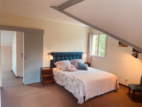 - une chambre avec un lit doté d'une tête de lit bleue et d'une fenêtre dans l'établissement L'orée des roses, hébergement de vacances avec jardin et piscine, à Gan