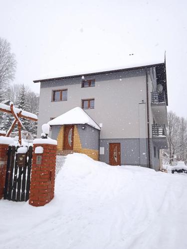 a building with snow on the ground in front of it at Kwatera u Stasia i Małgosi in Korbielów