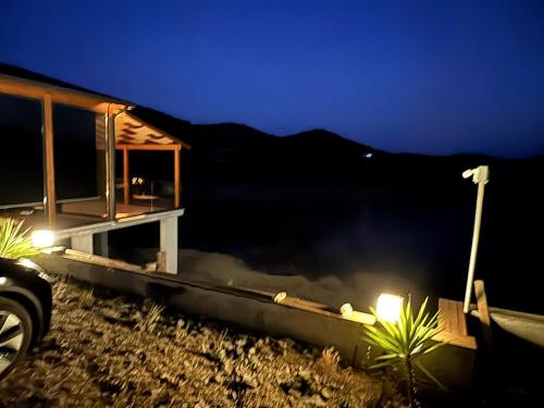 a house with lights on the beach at night at Meria Life Stone House with Lake View in Nature in Seferihisar