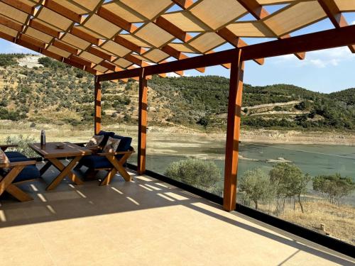 a patio with a table and a view of a river at Meria Life Stone House with Lake View in Nature in Seferihisar