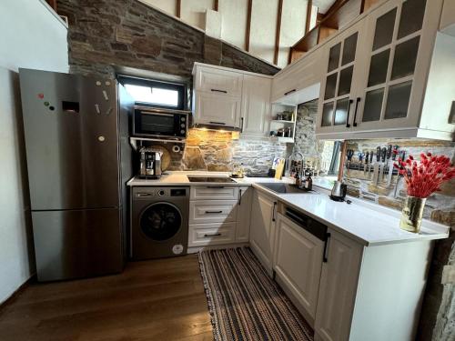 a kitchen with white cabinets and a refrigerator at Meria Life Stone House with Lake View in Nature in Seferihisar
