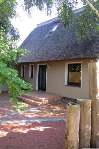 a house with a thatched roof and a patio at Strandhaus Möve in Wustrow