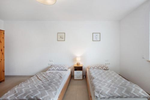 two beds in a room with white walls at Ferienwohnung am Klemmbach in Müllheim