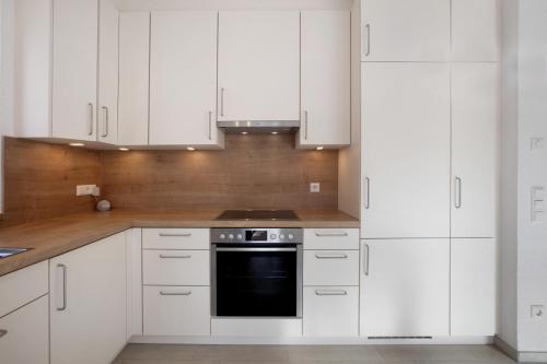 a kitchen with white cabinets and a stove at Ferienwohnung am Klemmbach in Müllheim