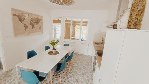 une cuisine avec une table blanche et des chaises bleues dans l'établissement Agréable maison avec jardin à 100m de la plage, à Berck-sur-Mer