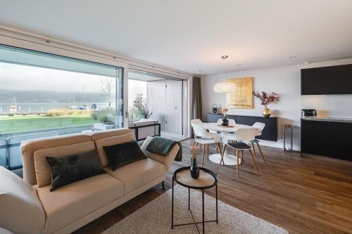 a living room with a couch and a table with chairs at Nautica Faulensee in Faulensee