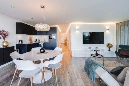 a living room and kitchen with a white table and chairs at Nautica Faulensee in Faulensee