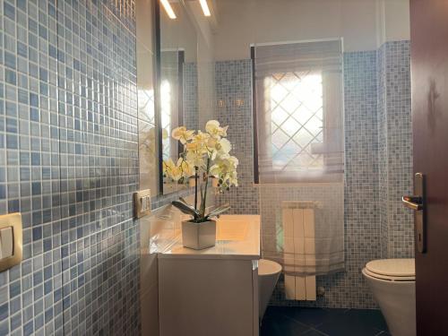 a bathroom with a toilet and a vase of flowers on a counter at Casa Letizia in Ladispoli