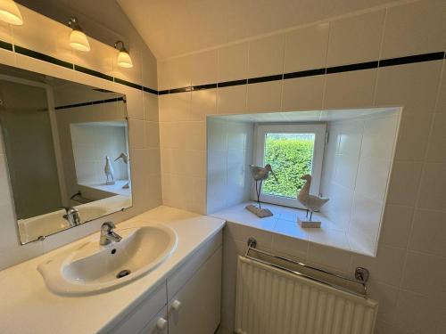 une salle de bain avec un lavabo, un miroir et une fenêtre dans l'établissement La Ferme Césarine, longère rénovée, wifi, jardin, à Carnac