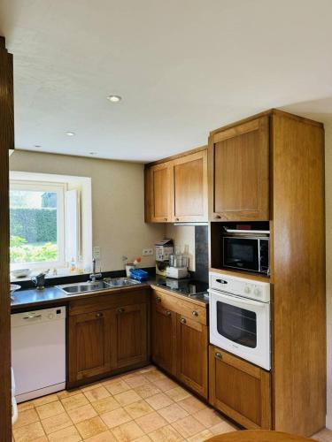 - une cuisine avec des placards en bois et des appareils blancs dans l'établissement La Ferme Césarine, longère rénovée, wifi, jardin, à Carnac