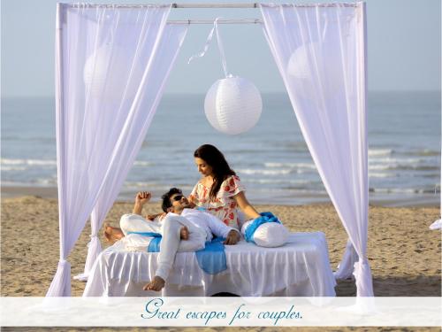 a group of people sitting on a bed on the beach at Serena Beach Resort in Mandvi