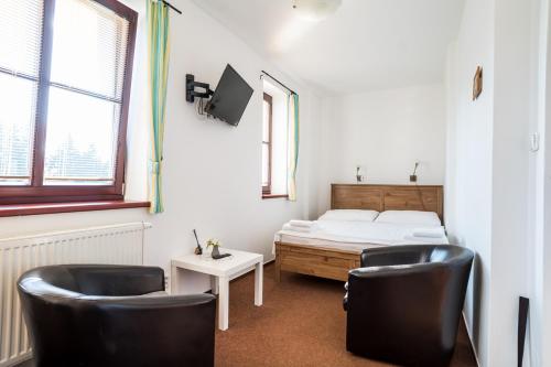 a room with a bed and two chairs and a table at Penzion Fialka in Velké Losiny