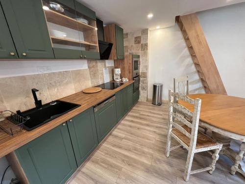 une cuisine avec des placards verts et une table en bois dans l'établissement Appart Montignac, à Montignac